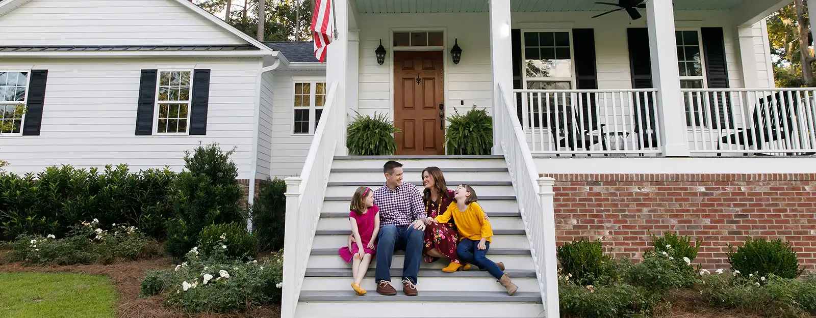 Family sits together on steps of home.