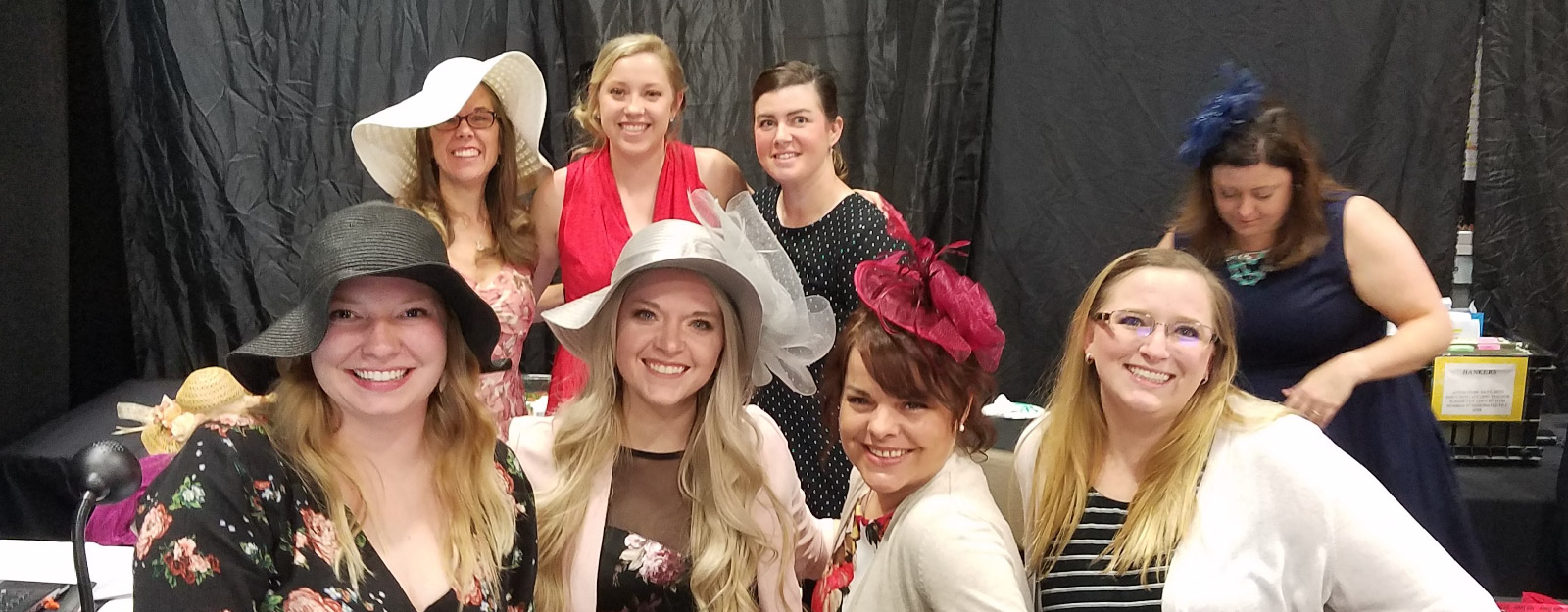 Women in hats smiling at auction