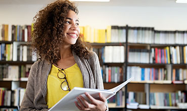 Woman smiling in library while holding book