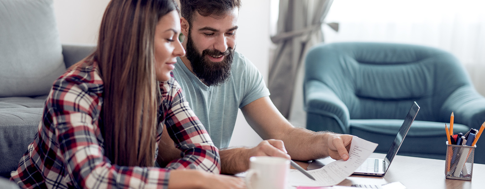 man and woman with computer looking at paper