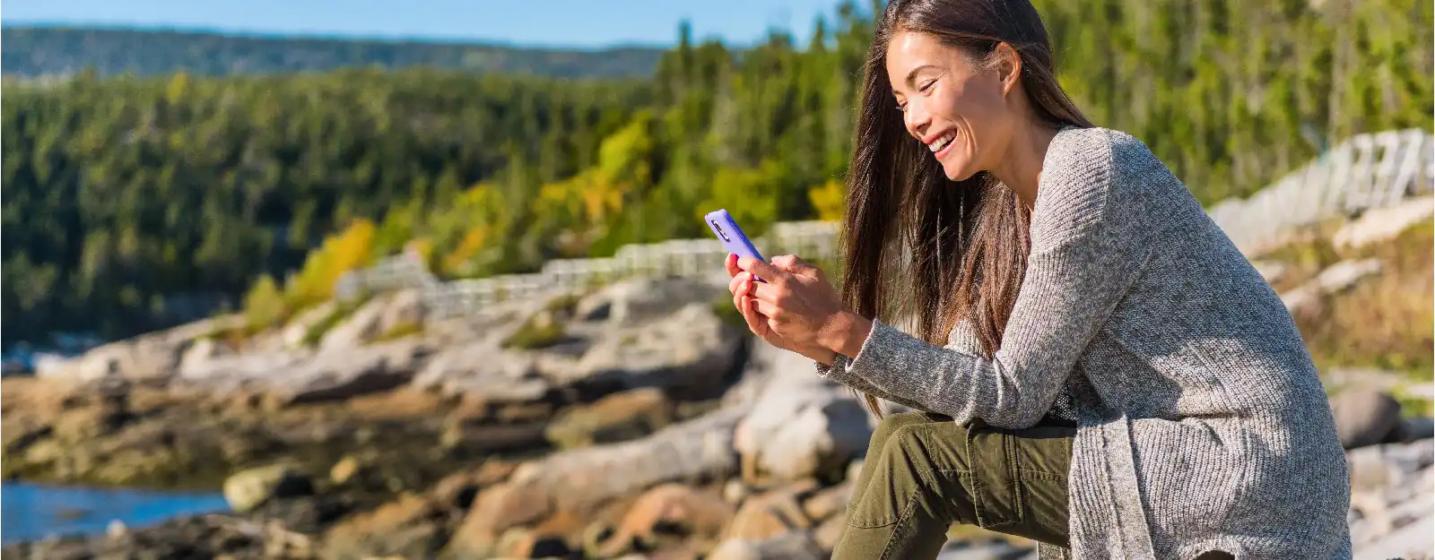 woman smiling at phone outdoors