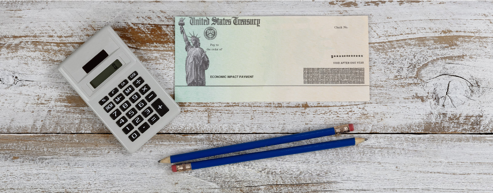 United States Treasury check, calculator, and pencils on desk