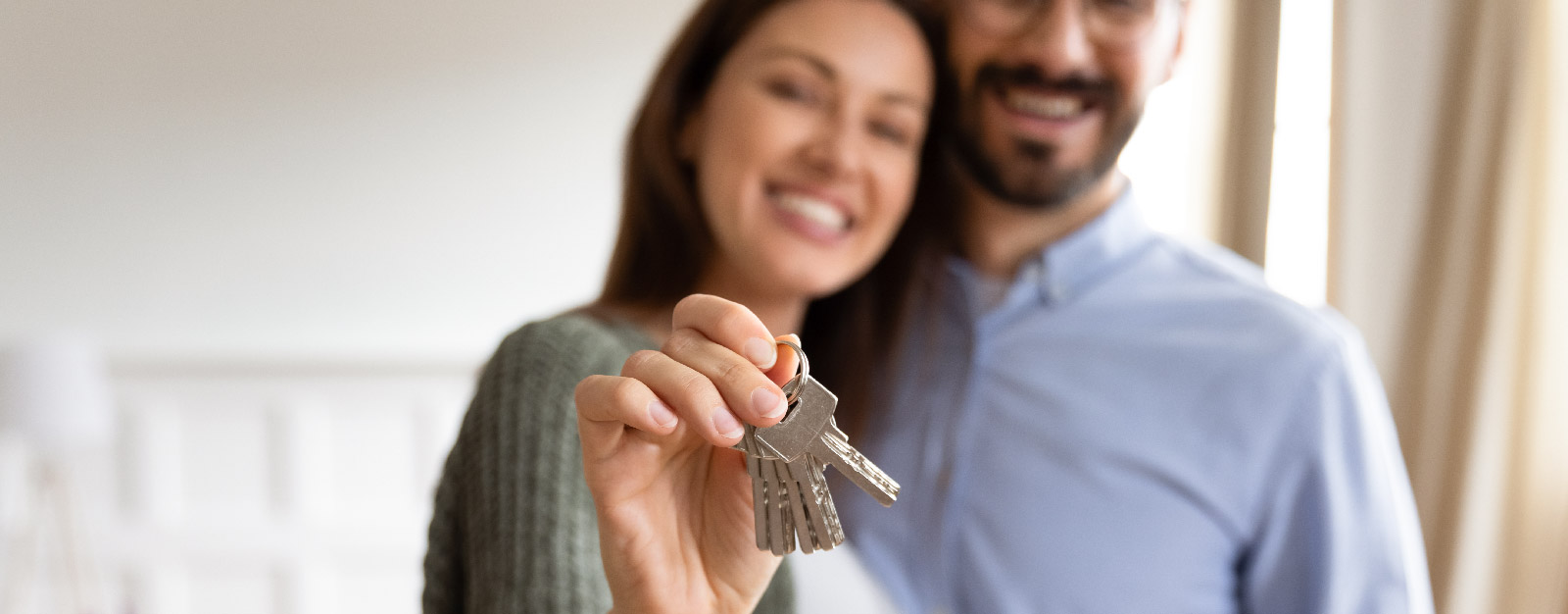 Man and woman smiling while holding keys to new home