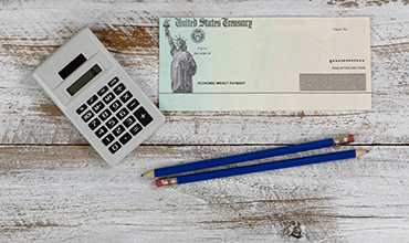 United States Treasury check, calculator, and pencils on desk