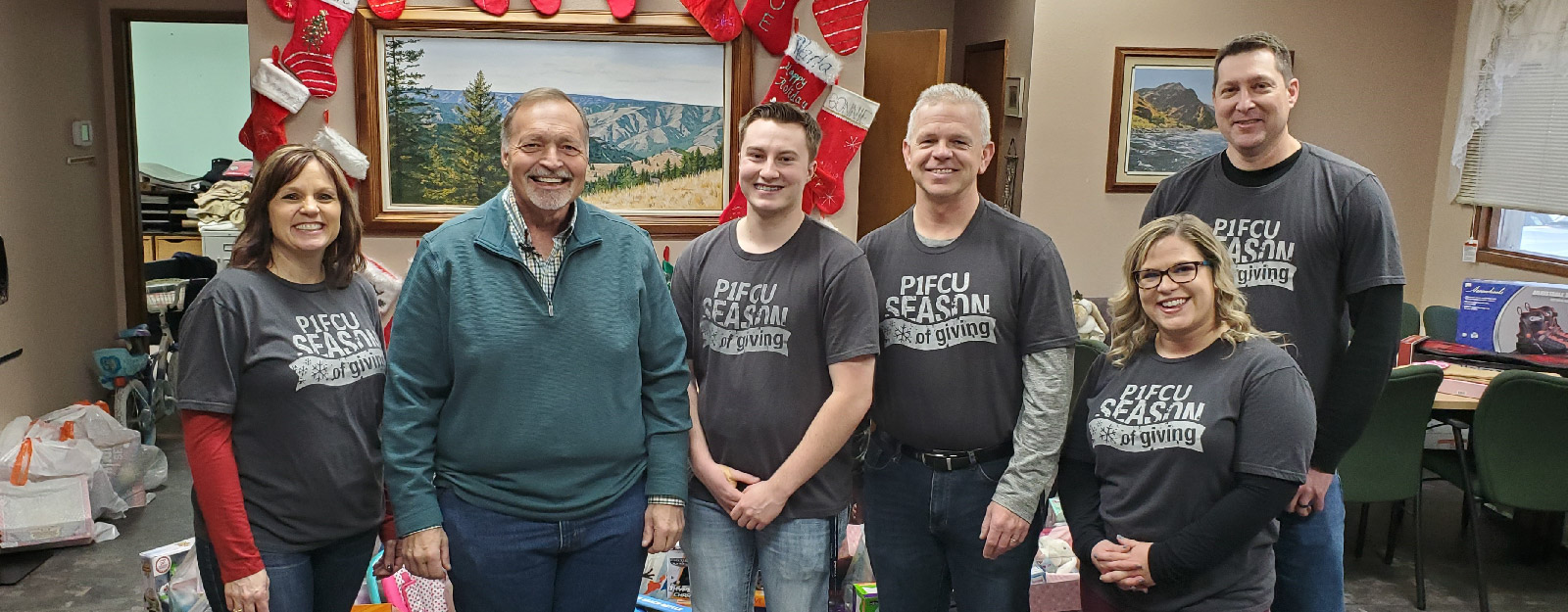 People in P1FCU shirts smiling for Christmas holiday photo