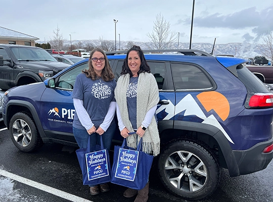 two women posing with bags in front of blue car