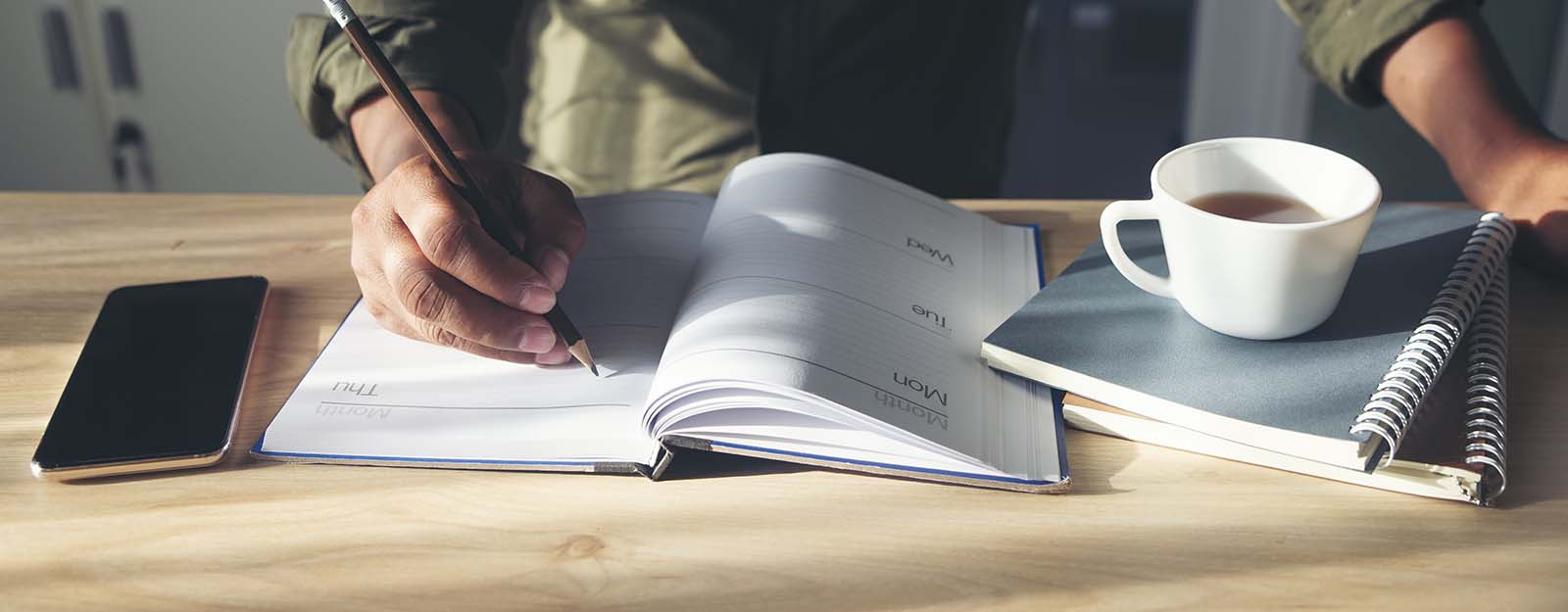 Person in cafe writing in planner